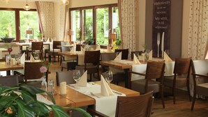 A restaurant with multiple tables set for dining, featuring wooden furniture and hanging pendant lights. - Landidyll Landaus Liesetal (Hallenberg)