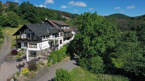 A traditional chalet with a stone foundation, wooden balconies, and a paved patio area. - Landidyll Landaus Liesetal (Hallenberg)