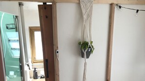 Ein Schlafzimmer mit einem Bett, einer Wanddekoration aus Makramee und einer Pflanze.