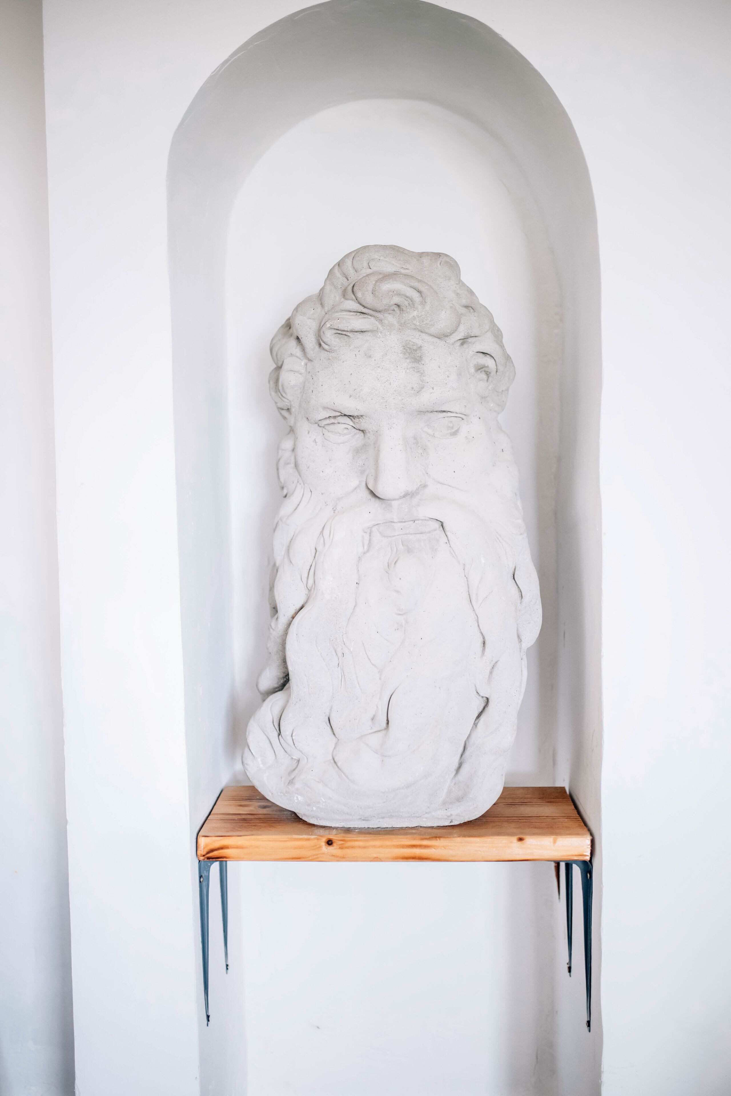 A white stone sculpture of a bearded figure in a white arched niche.