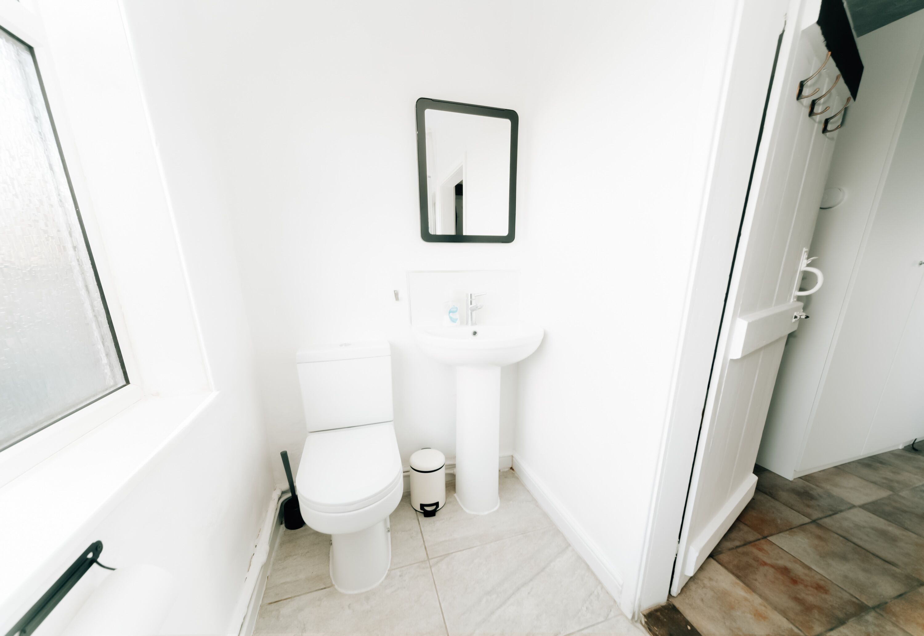 A small, white bathroom with a toilet, sink, and mirror.