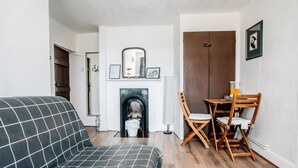 Un salon comprenant un canapé, une cheminée, une table à manger avec des chaises et une porte.