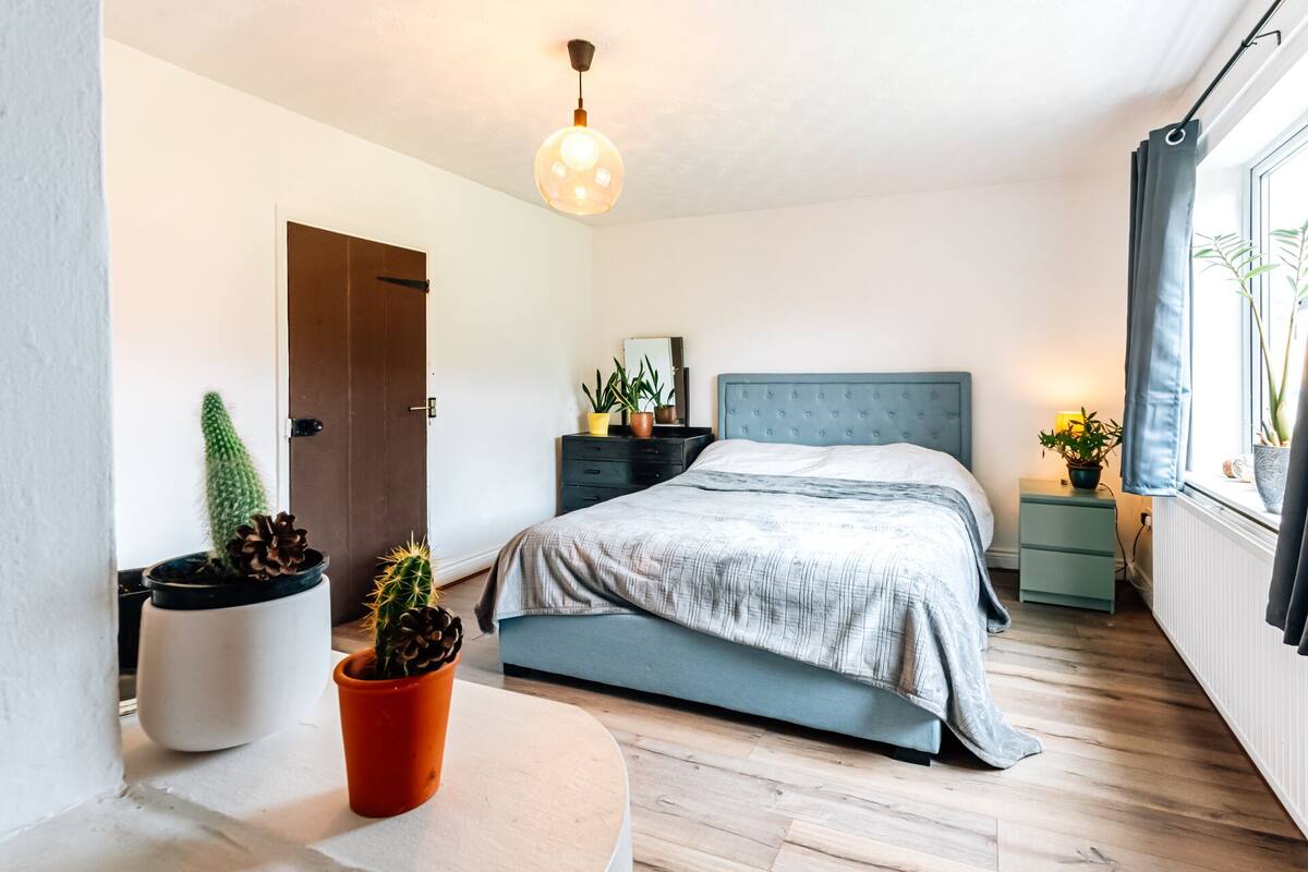 A bedroom with a bed, bedside tables, a dresser, and a window with curtains.