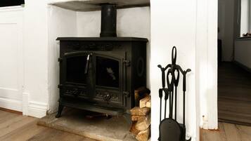 A black wood-burning stove in a white-walled room with a wooden floor.