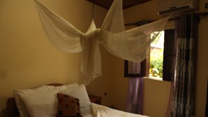 Una cama con dosel, una ventana con cortinas y un equipo de aire acondicionado.