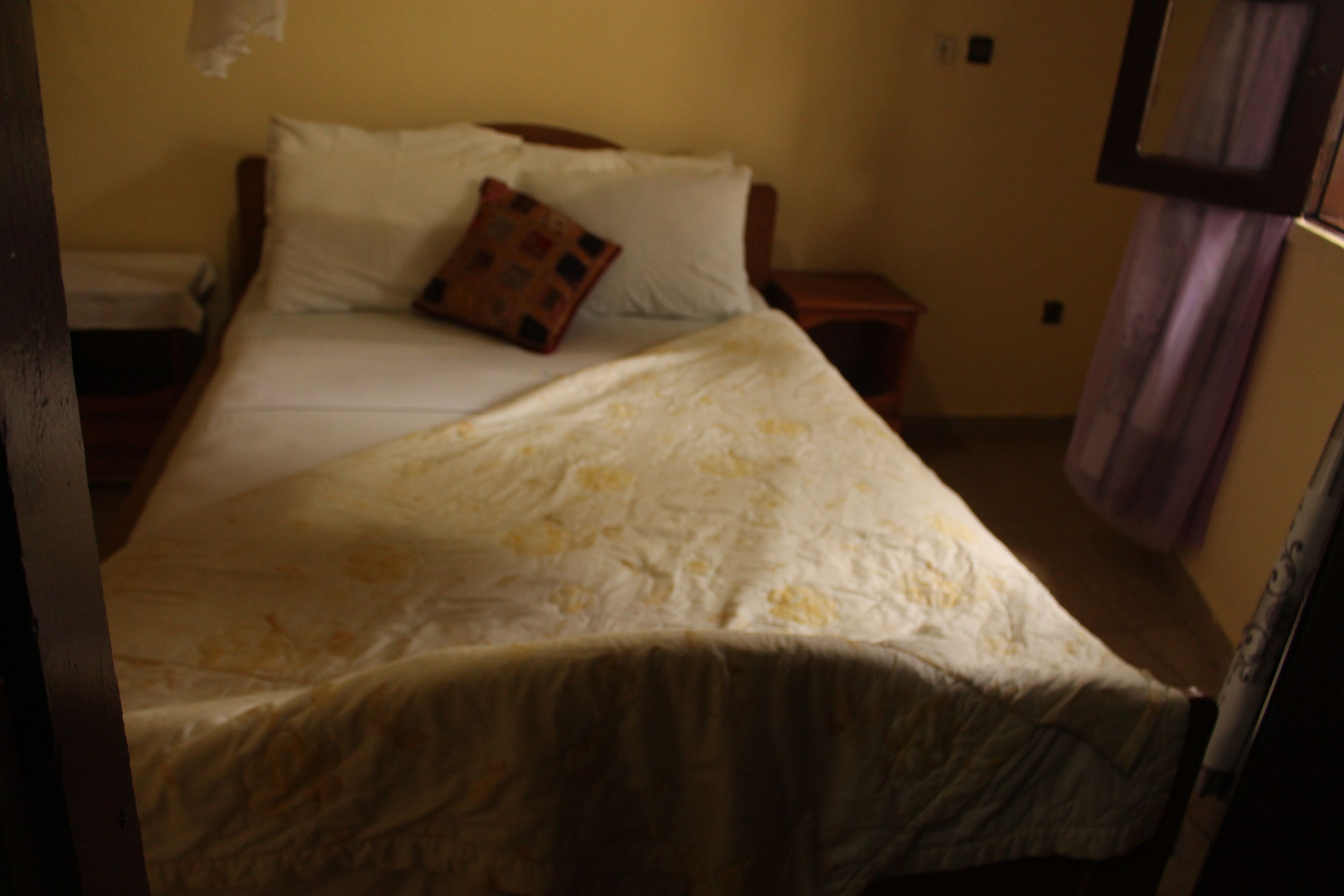 Una cama con un edredón estampado, una almohada y una mesita de noche con una lámpara.