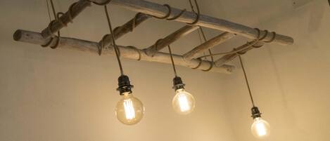 A ceiling with three exposed wooden beams supporting hanging light bulbs.