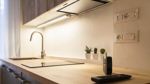 A modern kitchen with a built-in sink, a faucet, a countertop, and a wall-mounted power outlet. - Lovely Studio D'azeglio (Bologna)