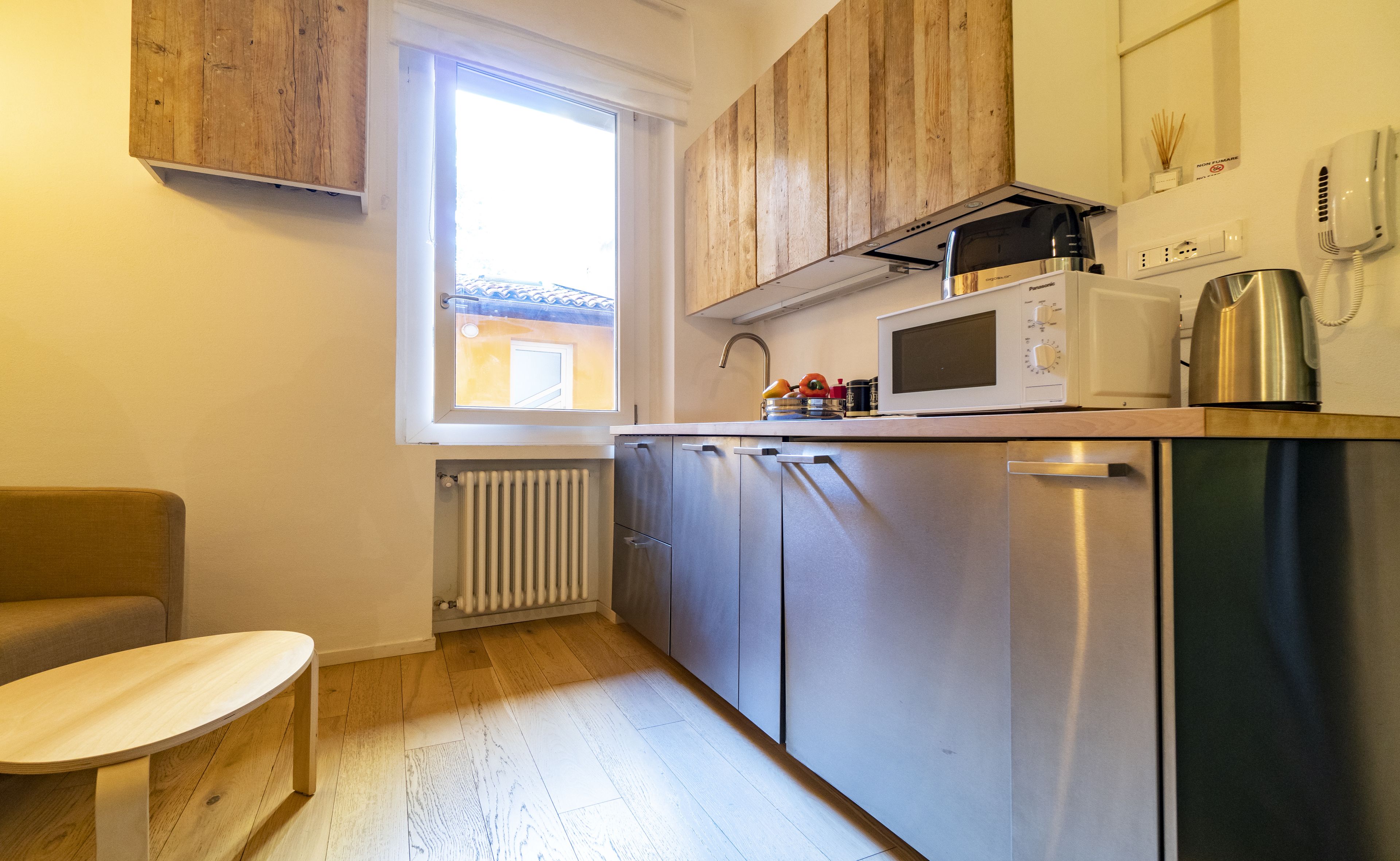 A compact kitchen with wooden cabinets, a built-in microwave, and a kettle.