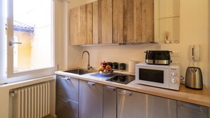 A kitchen with wooden cabinets, a microwave, a coffee maker, and a kettle. - Lovely Studio D'azeglio (Bologna)