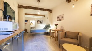 A compact living space with a kitchenette, a bed, a sofa, and a small table. - Lovely Studio D'azeglio (Bologna)