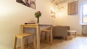 A room with a wooden table, two chairs, a vase with flowers, and a hanging light fixture. - Lovely Studio D'azeglio (Bologna)