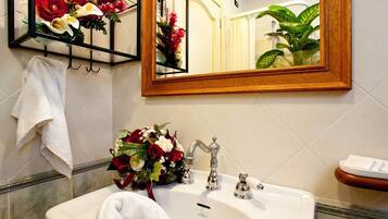 Un baño con un lavabo blanco, un espejo y un perchero para toallas.