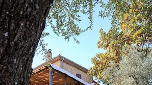Una casa de piedra rústica con un porche de madera y un muro de ladrillo.