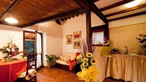 Un comedor acogedor con techo de madera, una mesa con mantel rojo y un jarrón de girasoles.