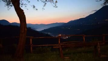 Una valla de madera en un entorno natural, con vistas a montañas distantes y luces en el valle.