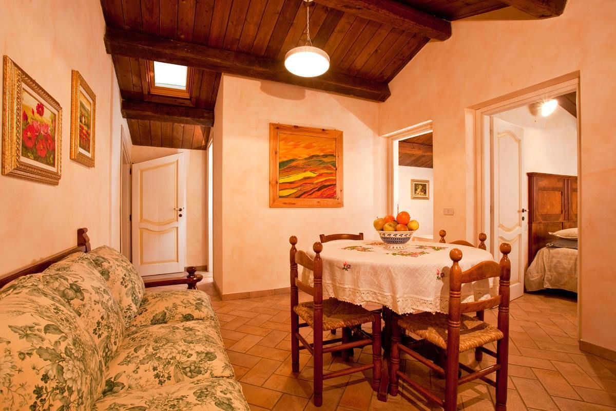 Un rincón comedor acogedor con una mesa de madera, sillas y un sofá floral.