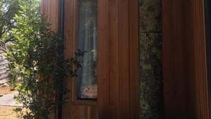 A wooden cabin with a large tree in front, a door, and a window. - Villa Andernos (Andernos-les-Bains)