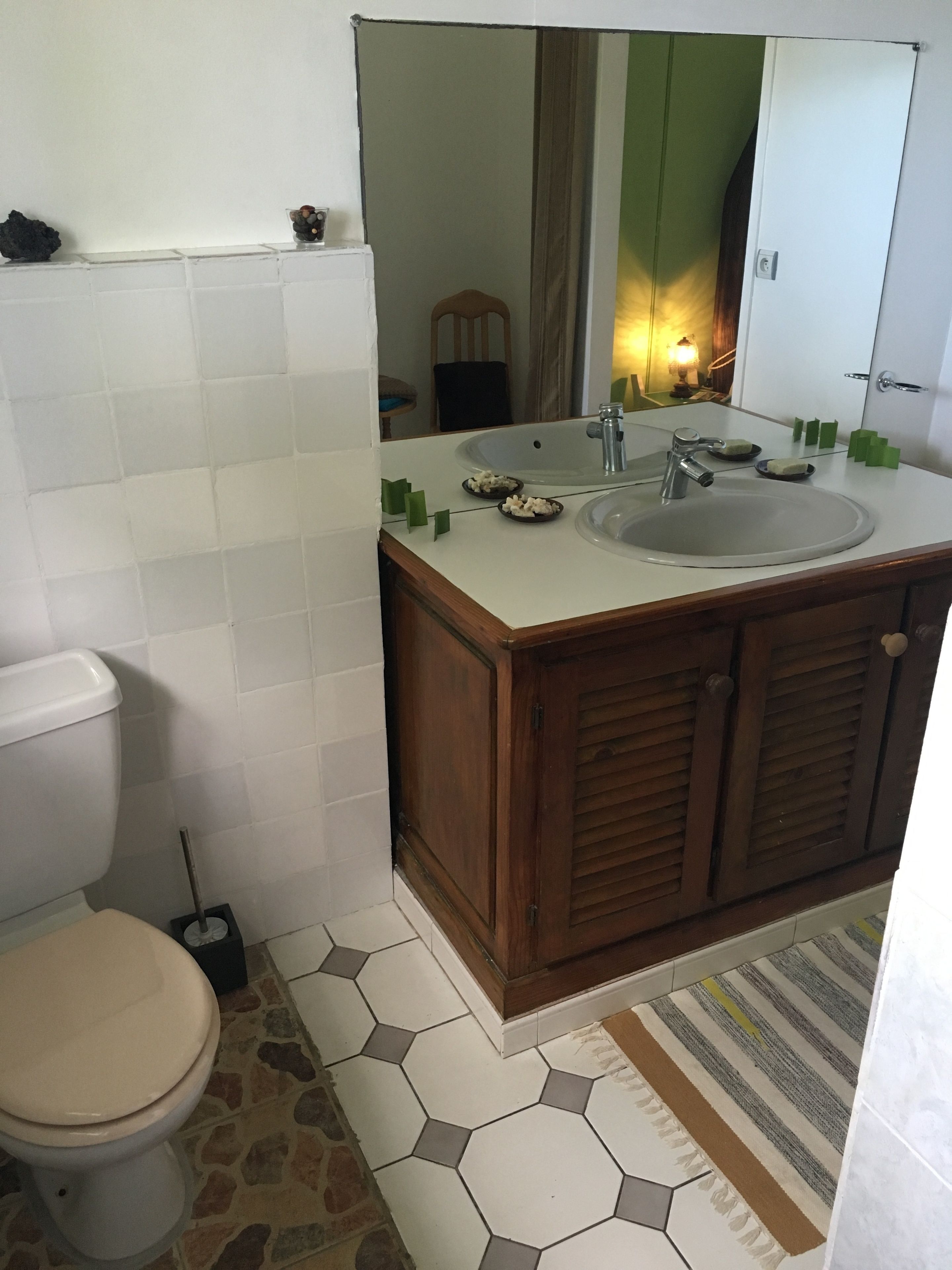 A bathroom with a toilet, a sink with a mirror, and a wooden cabinet.