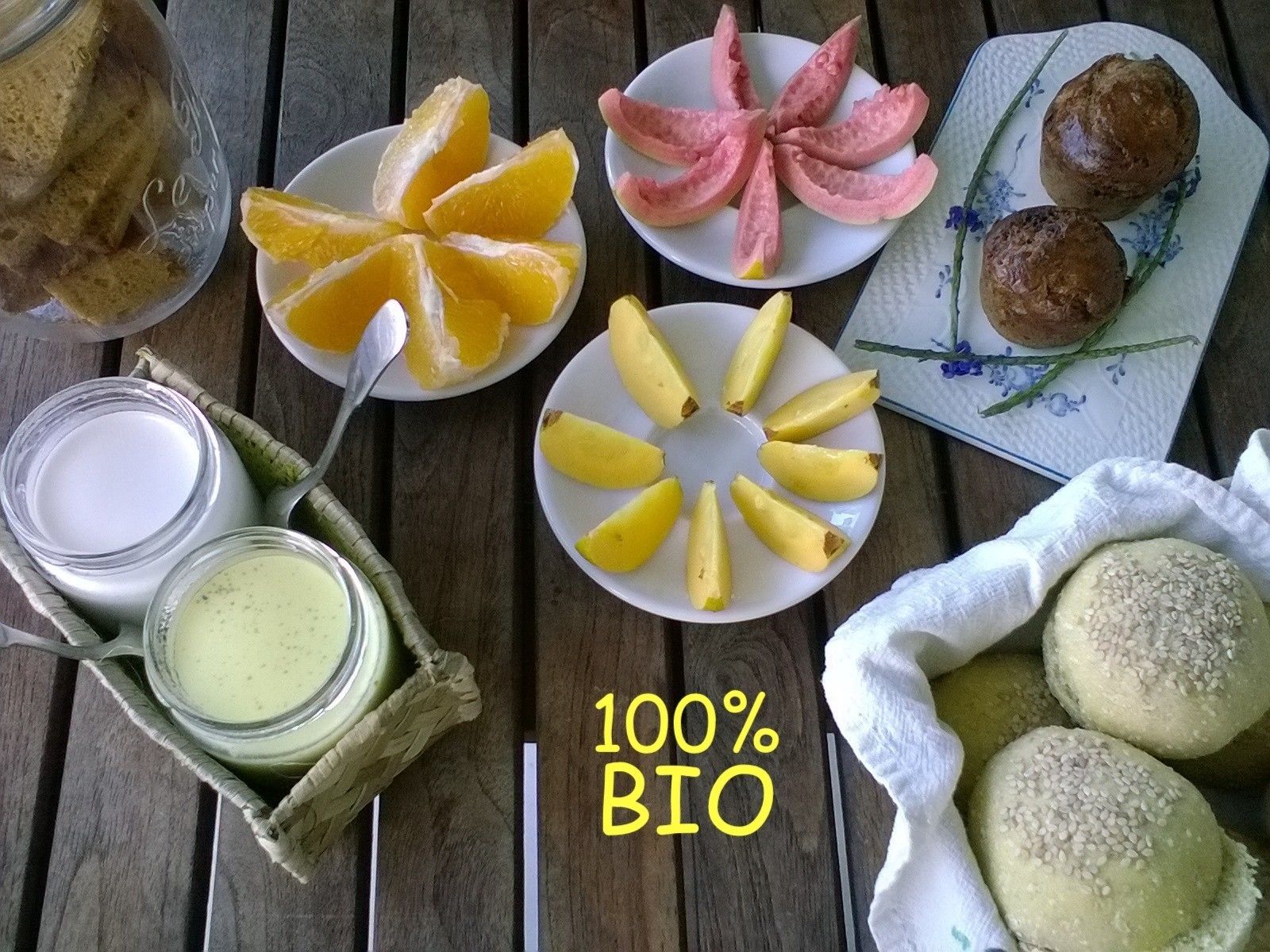 Et træbord med forskelligt mad, blandt andet brød, skiver af citrusfrugter og et fad med kager.