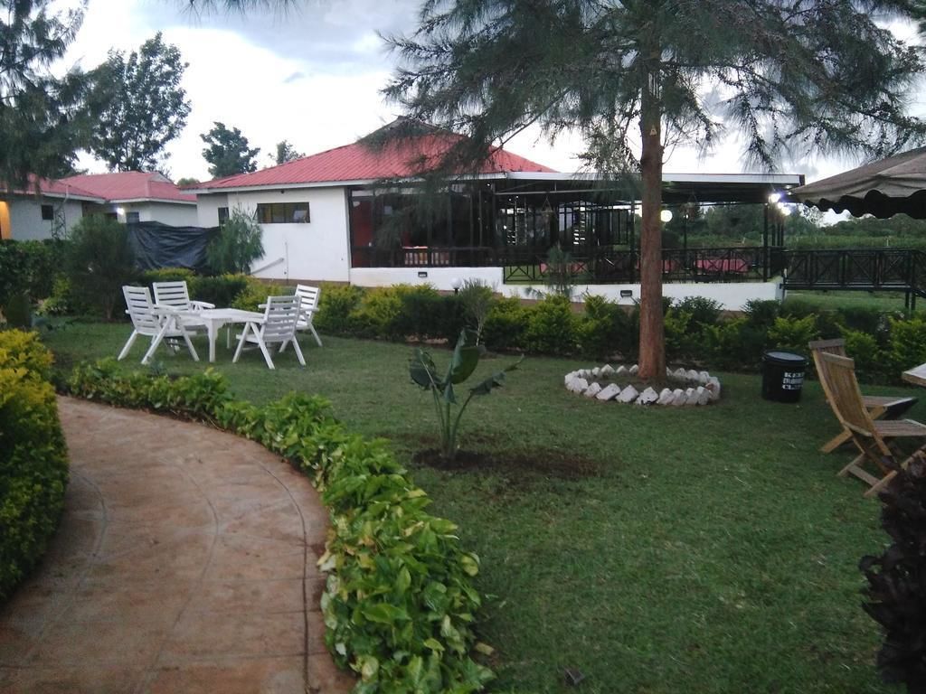 A hotel with a covered outdoor seating area, a lawn, and a pathway.