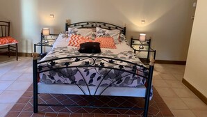 A bed with a floral-patterned bedspread, two bedside lamps, and a headboard with a light fixture above. - Champagne Urbain (Baroville)