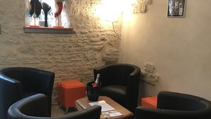 A cozy living area with stone walls, a wooden table, and black armchairs. - Champagne Urbain (Baroville)