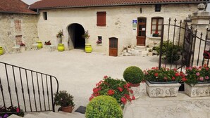 A stone building with a red-tiled roof, a central archway, and a staircase leading to the entrance. - Champagne Urbain (Baroville)