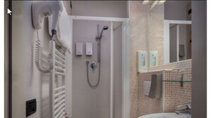 Un baño con ducha, lavamanos y espejo.