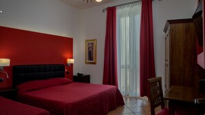 Habitación de hotel con dos camas, un armario de madera, un escritorio y una silla.