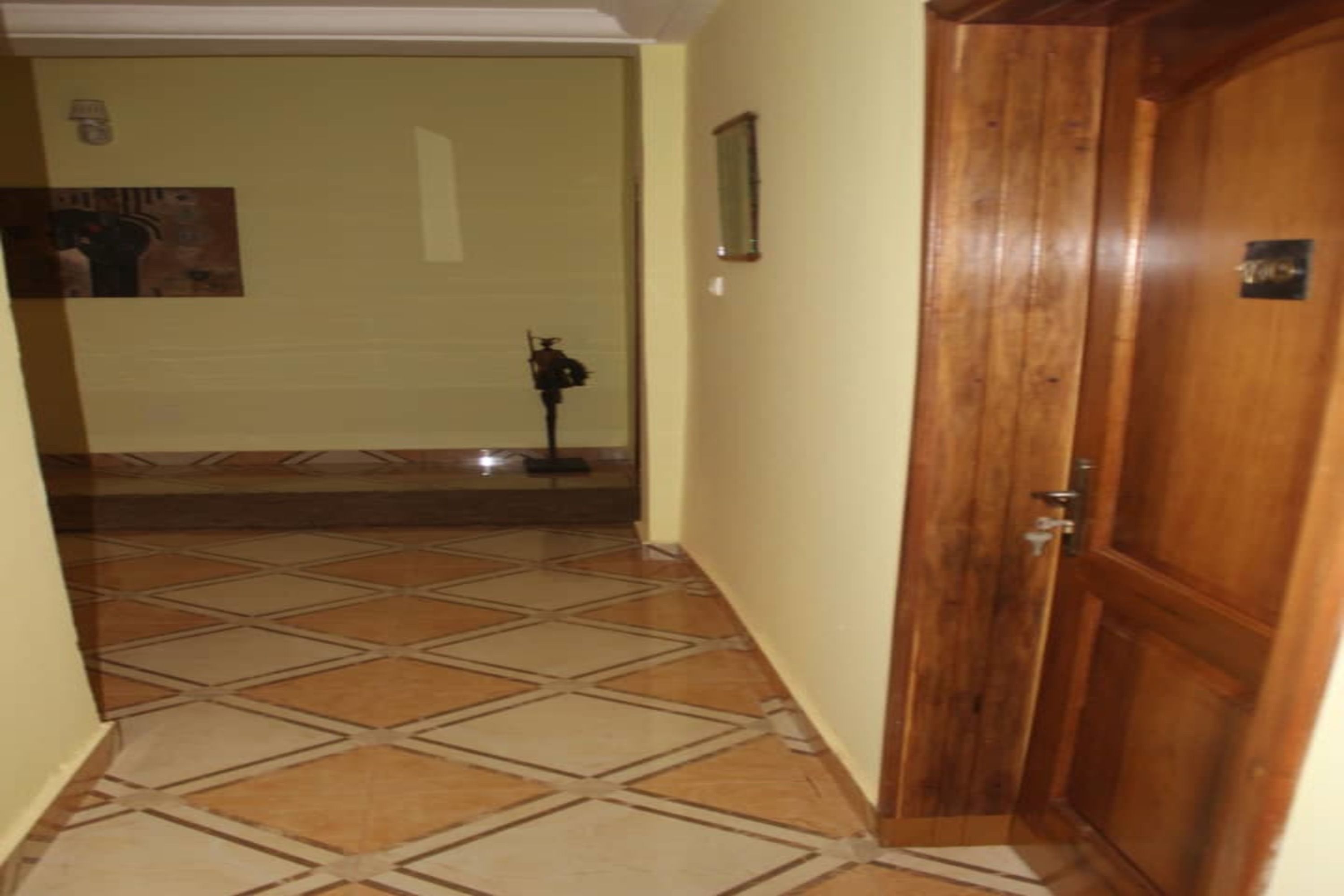 A hallway with a tiled floor and a wooden door.