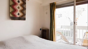 A hotel room with a bed, a window with curtains, and a balcony with a chair. - Cerviño y Bulnes 3 (Buenos Aires)
