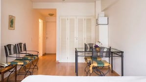 A room with a bed, a table with chairs, a telephone, and a door leading to another room. - Cerviño y Bulnes 3 (Buenos Aires)