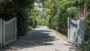 A paved pathway flanked by white gates, surrounded by dense greenery. - Diekhuus Arngast, Apartment Butendiek - Apartment Butendiek in the Diekhuus (Varel)
