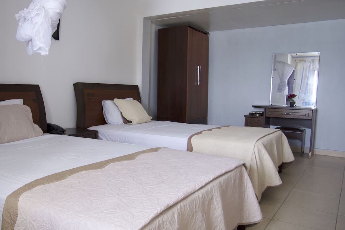 A hotel room with two beds, a desk, and a mirror.