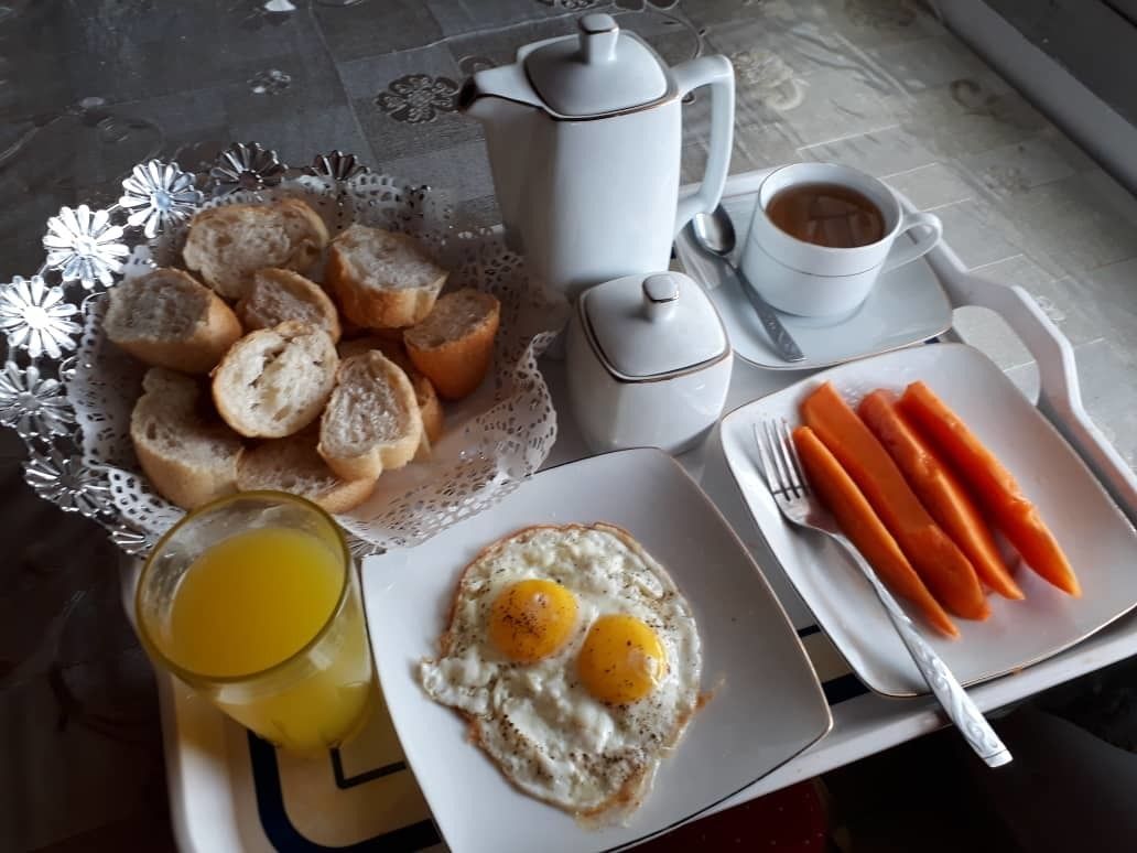 A breakfast tray with toast, eggs, carrots, and a cup of coffee.