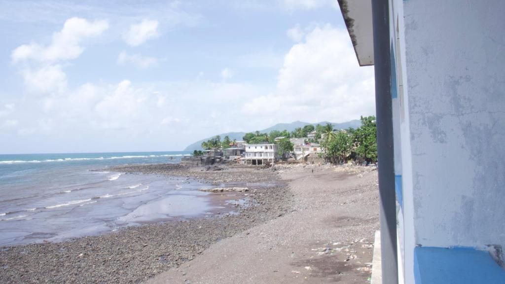 A beach with a building and palm trees in the background.