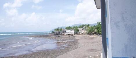 A beach with a building and palm trees in the background.