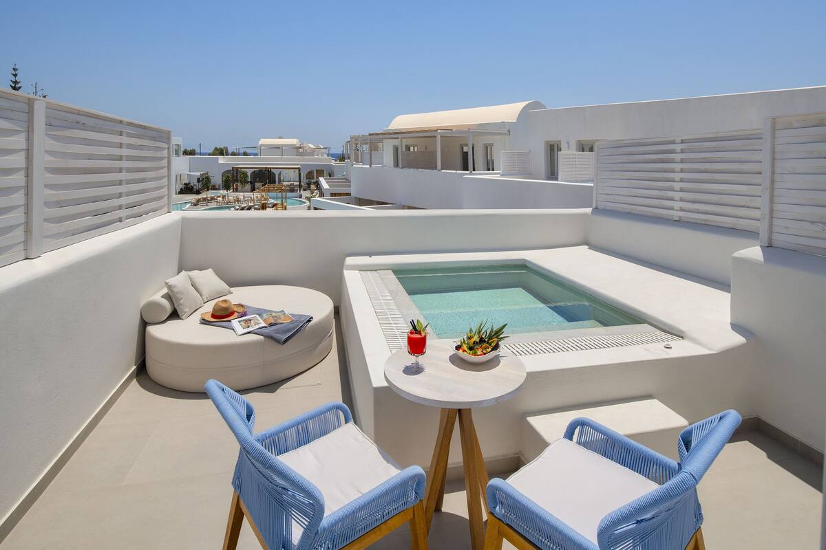 A rooftop terrace with a pool, seating area, and a table with drinks.