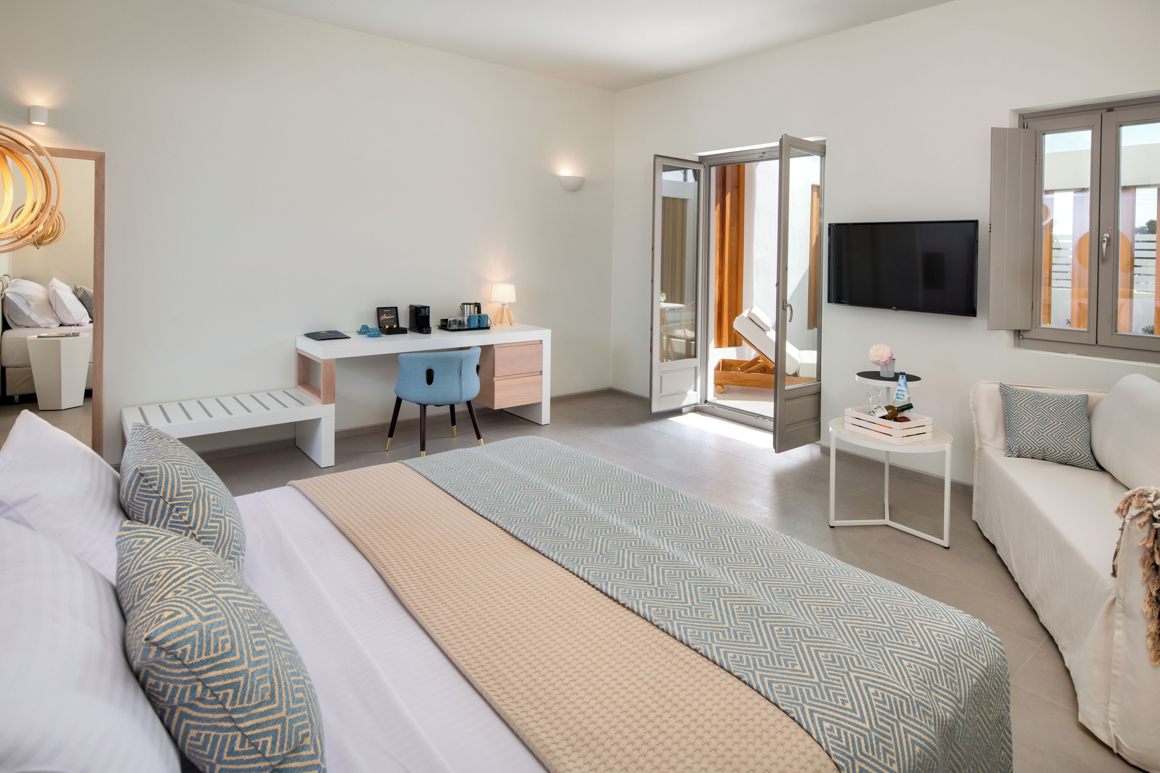 A modern hotel room with a bed, desk, and seating area.