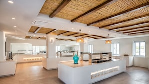 A modern kitchen with a central island, white cabinetry, and a wooden ceiling. - Meltemi Blu - Adults Only (Santorini)