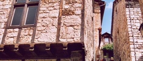 Un estrecho edificio de piedra con puerta de madera y un letrero.