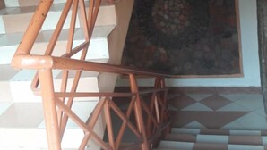 Un escalier dont le sol est orné d’un motif géométrique et qui possède une main courante en bois.