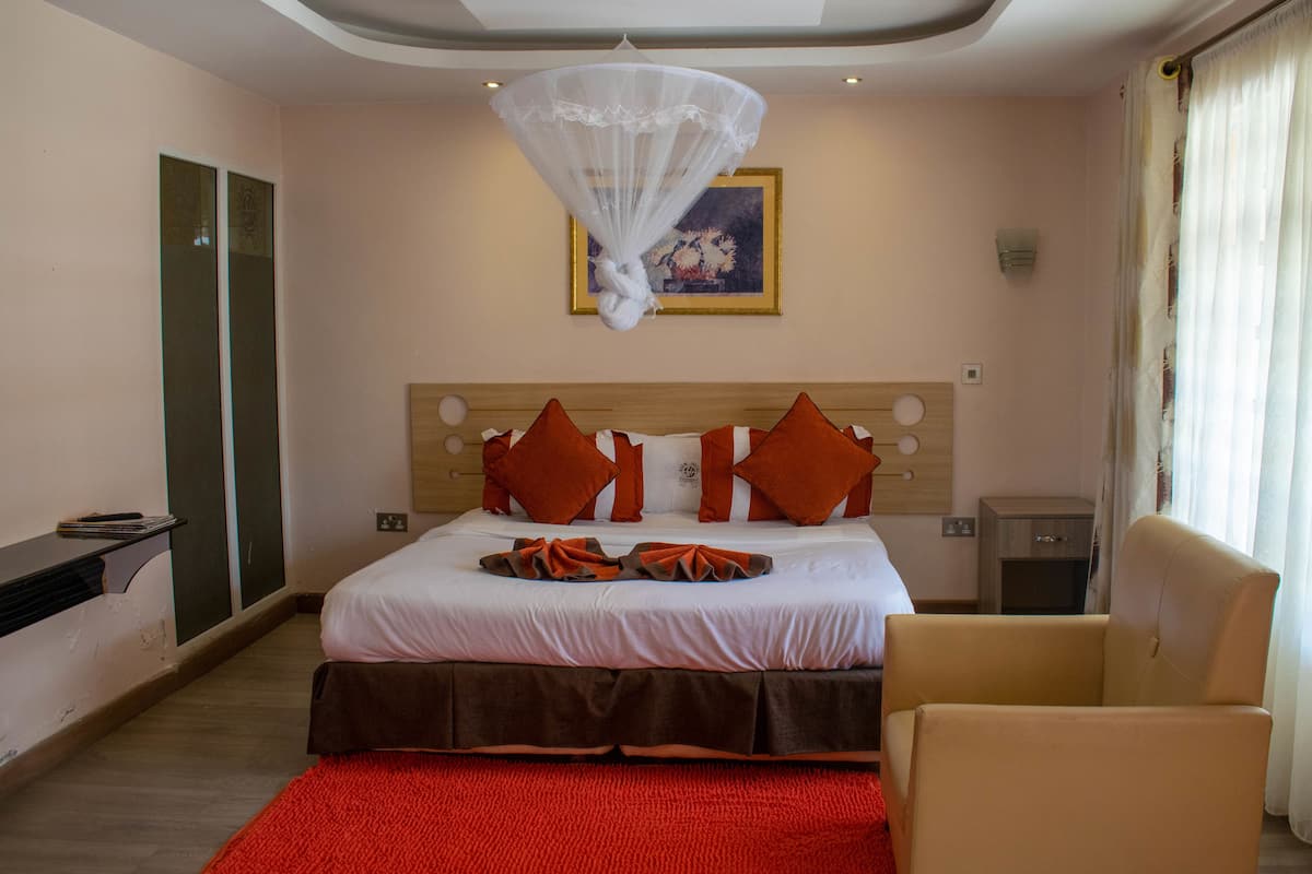 Una habitación de hotel con una cama, una silla, una mesita de noche y una obra de arte colgada en la pared.