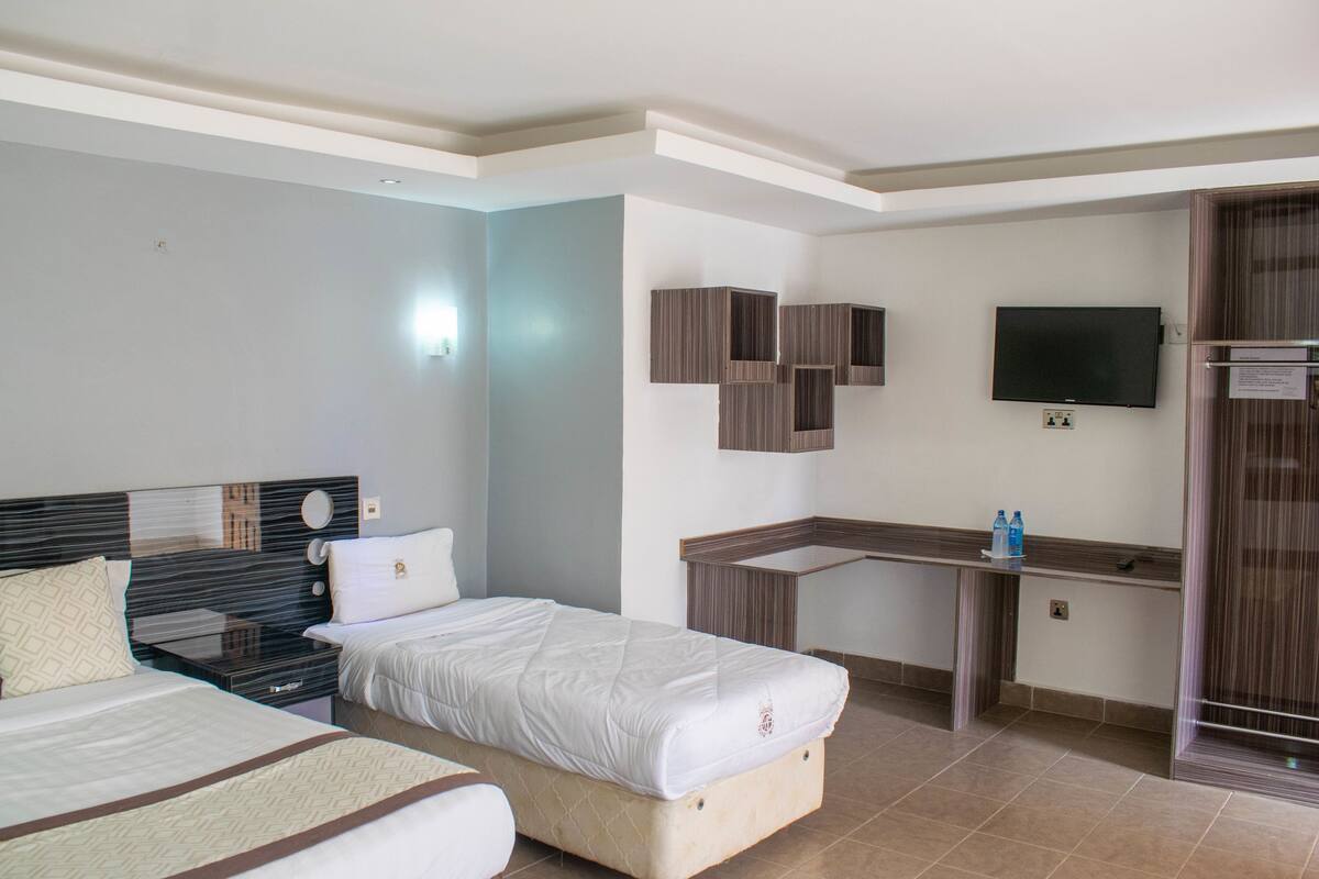Habitación de hotel con dos camas, un escritorio, un televisor y un mini bar.
