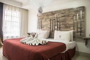 A hotel room with a large bed, a wooden headboard, and a window with curtains. - Stem Hotel (Nakuru)