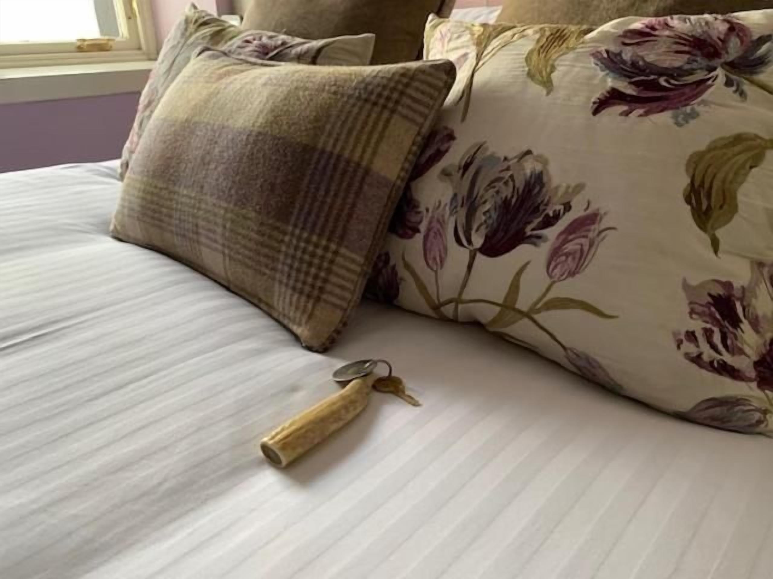 A bed with floral-patterned pillows and a key on the bed.