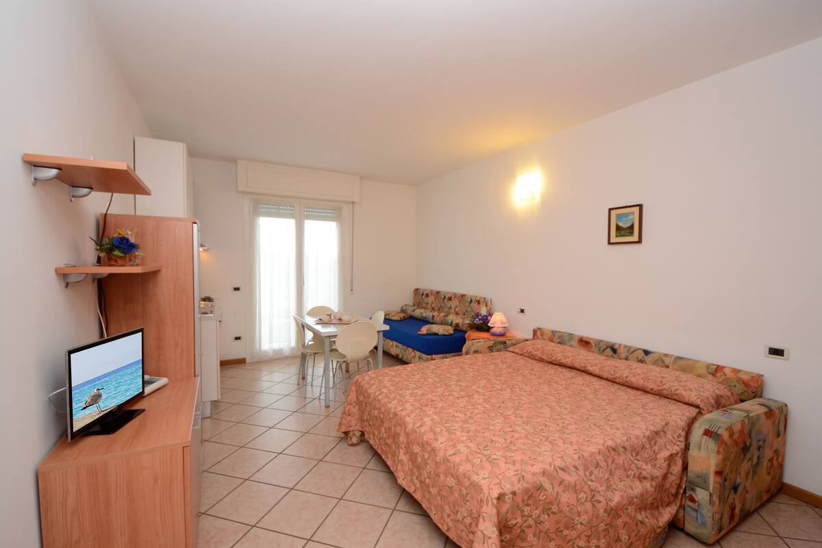 Un dormitorio con una cama, un escritorio y una televisión.
