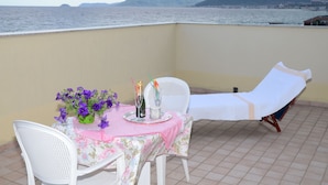 A balcony with a table set for two, a chair, and a sun lounger. - Residence Villa Gloria (Borgio Verezzi)