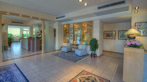 A spacious living area with a glass partition, a coffee table, a sofa, and a decorative lamp. - Residence Villa Gloria (Borgio Verezzi)